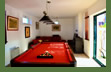 The games room has a billiards table, sitting area with sofa. board games, tv, and bar